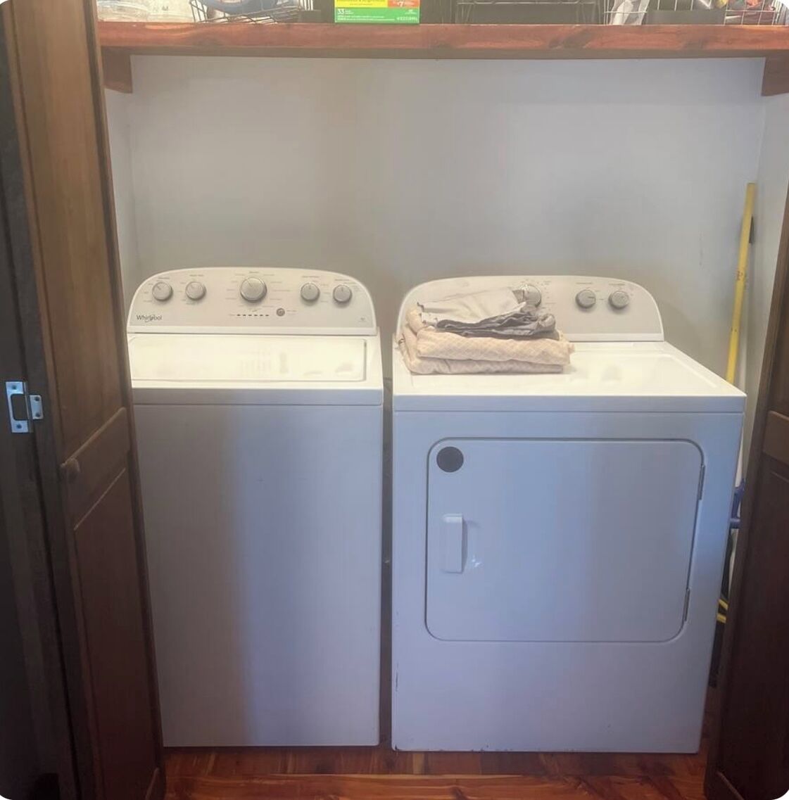 A laundry area with two stacked washers and dryers, a wooden floor, and a metal railing.