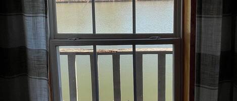 A window with a view of a body of water and a wooden deck.