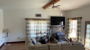 Un salon comprenant un canapé, un téléviseur, une cheminée et un ventilateur de plafond.