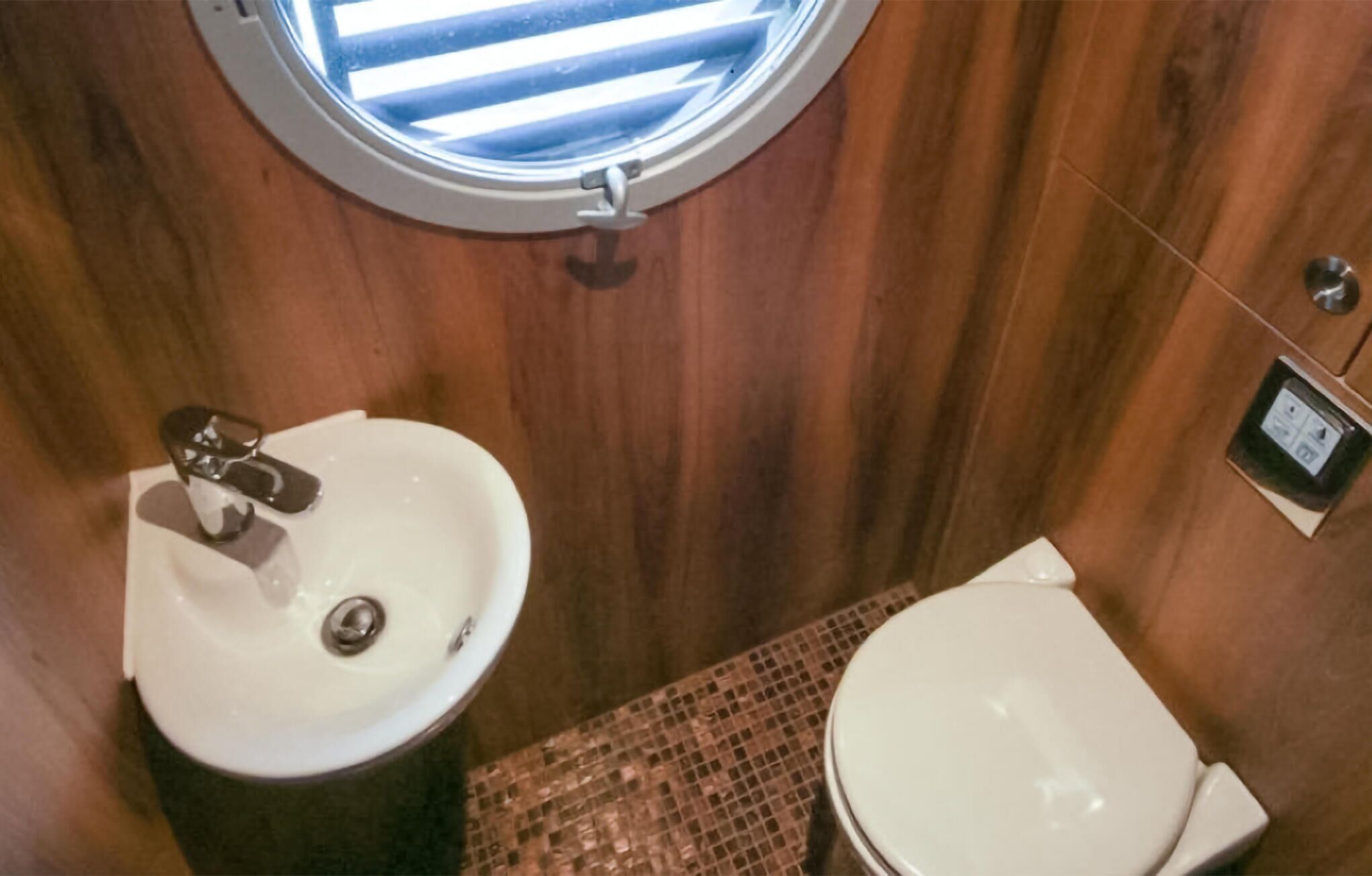 Un bagno piccolo con un oblò rotondo, un lavandino e un water.