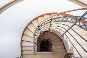 Una escalera en espiral con barandilla de hierro forjado y peldaños de piedra.