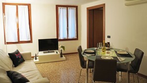 A living room with a sofa, TV, and dining table set for two.