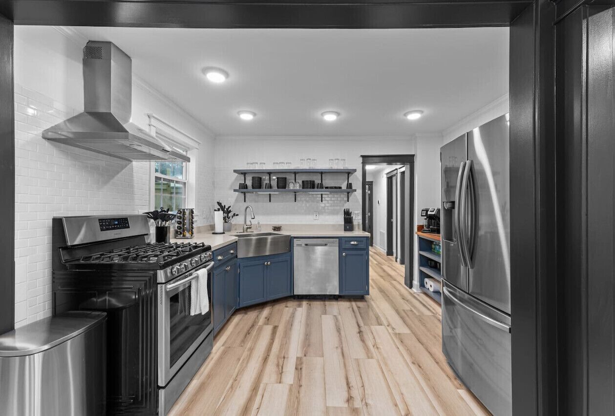 A modern kitchen with a stove, sink, dishwasher, and refrigerator.