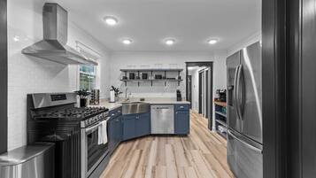 A modern kitchen with a stove, sink, dishwasher, and refrigerator.