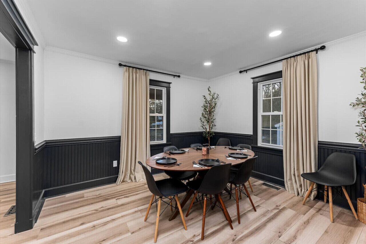 A conference room with a round table, black chairs, and beige curtains.
