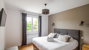 A bedroom with a large bed, a window with curtains, a bedside table, and a wall-mounted light fixture. - 4 bedroom lovely home in Cancale (Cancale)