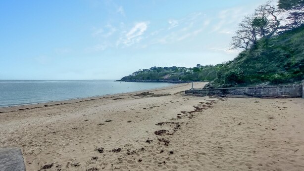 A sandy beach with footprints and seaweed, a clear sky, and a rocky outcrop with vegetation in the background. - 4 bedroom lovely home in Cancale (Cancale)