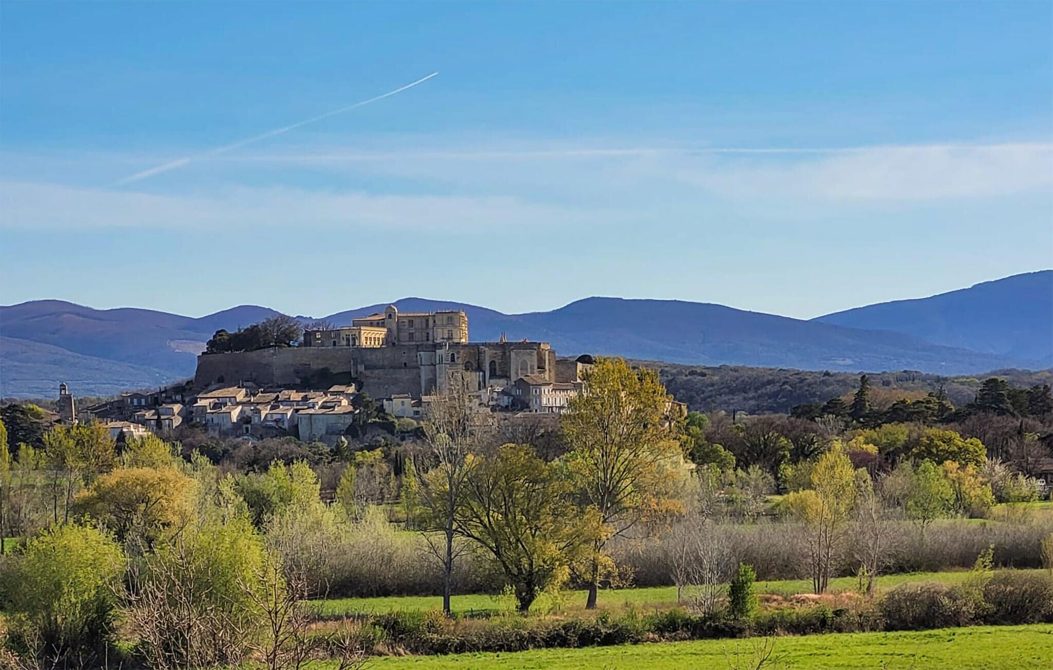 Un castello storico circondato da una vegetazione rigogliosa e montagne.