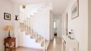 Eine Treppe führt zu einer zweiten Etage, ein kleiner Tisch mit einer Lampe und ein an der Wand befestigter Kleiderhaken.