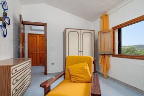 Een kamer met een houten stoel, een kledingkast en een raam met uitzicht.