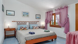 Ein Schlafzimmer mit einem Bett, Nachttischen, einem Fenster mit Vorhängen und Bildern an der Wand.