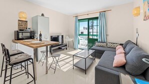 Een moderne woonkamer met een grijze bank, een houten eettafel en een televisie.