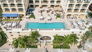 A hotel with a central swimming pool, multiple balconies, and outdoor seating areas.