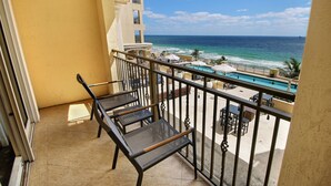 A balcony with a view of the ocean and a pool area.
