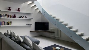 A modern living room with a staircase, bookshelves, a flat-screen TV, and a sofa. - SWEETHOME MUSEUM 190sqm with Garage in the heart of Bolzano (Bolzano)