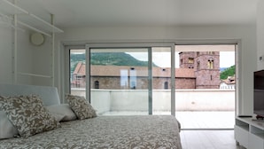 A bedroom with a large bed, a TV, and a view of a building with a tower. - SWEETHOME MUSEUM 190sqm with Garage in the heart of Bolzano (Bolzano)