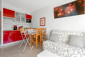 Un espacio habitable compacto con kitchenette, comedor y sofá de tapicería estampada.