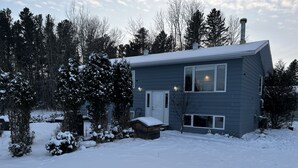 A two-story house with a snow-covered roof and yard, surrounded by trees. - Cozy Country Living (Nipawin)