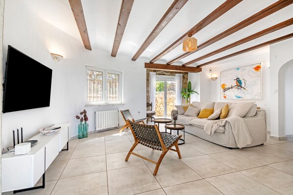A living room with a sofa, a chair, a TV, a table, and a painting on the wall.