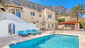 A poolside area with lounge chairs, a pergola, and a mountain backdrop. - Villa Adriana with Sea View, Mountain View, Wi-Fi and Air Conditioning (Dénia)