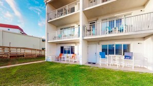 Un immeuble à plusieurs étages doté de balcons, d’un espace extérieur aménagé pour s’asseoir et d’une zone verdoyante.