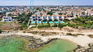A coastal residential area with multiple houses, a sandy beach, and clear blue waters. - Villa Posidonia - 200m from Sandy Beach (Ayia Napa)