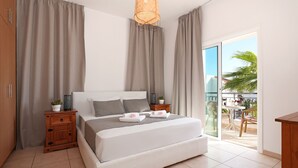A bedroom with a large bed, wooden nightstands, a potted plant, and a view of a balcony with outdoor furniture. - Villa Posidonia - 200m from Sandy Beach (Ayia Napa)
