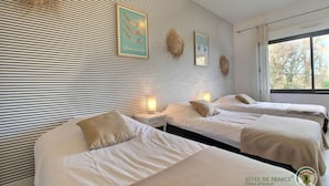 A hotel room with two beds, a striped wall, and a window with a view.