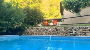 Una piscina con un muro de piedra y una valla de madera.