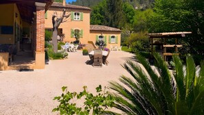 Un edificio rústico con un patio, asientos al aire libre y vistas a una ladera boscosa.