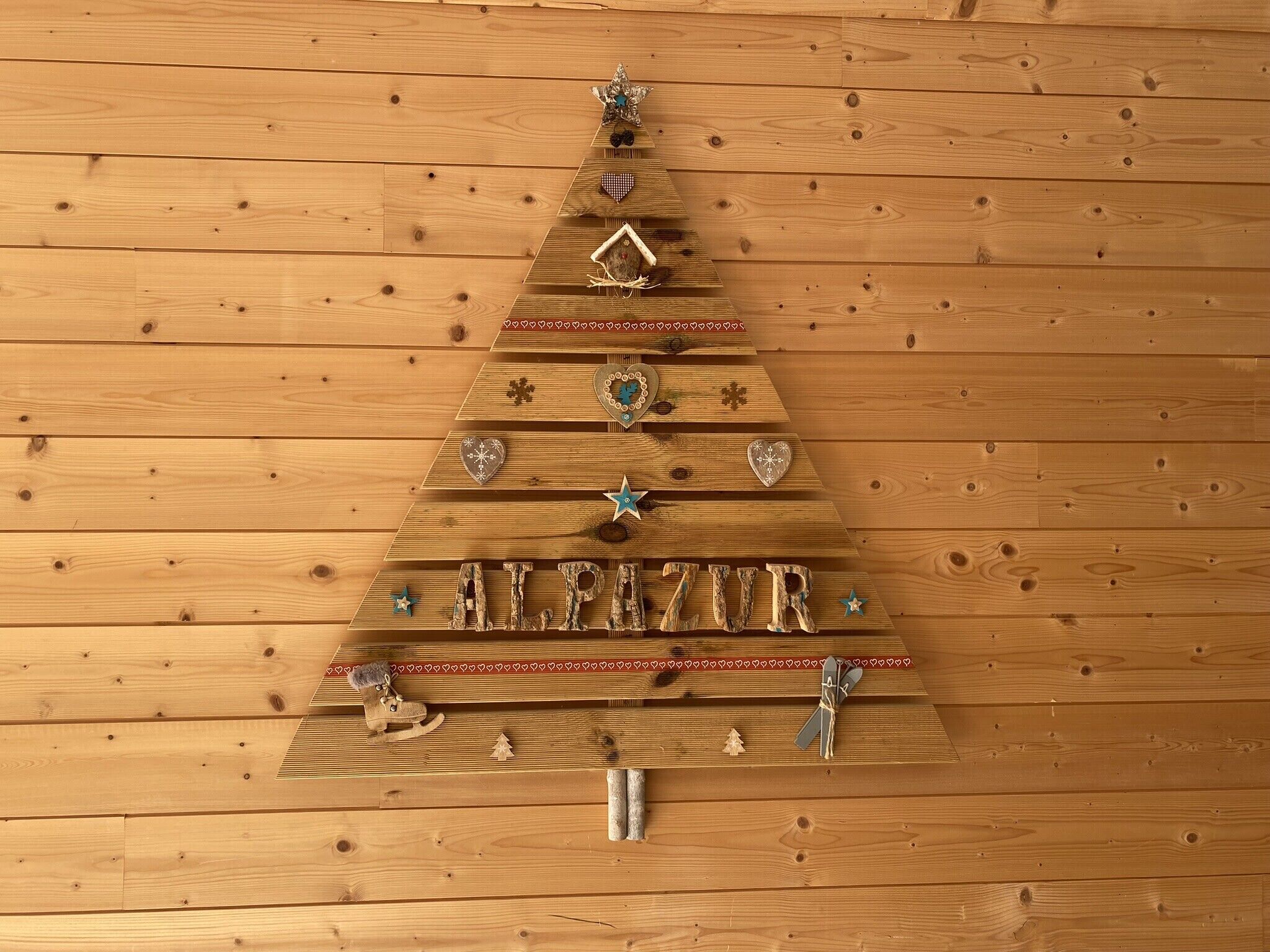 Uma árvore de Natal de madeira decorada, com a palavra 'ALPAZAR'.