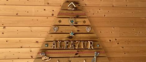 Uma árvore de Natal de madeira decorada, com a palavra 'ALPAZAR'.