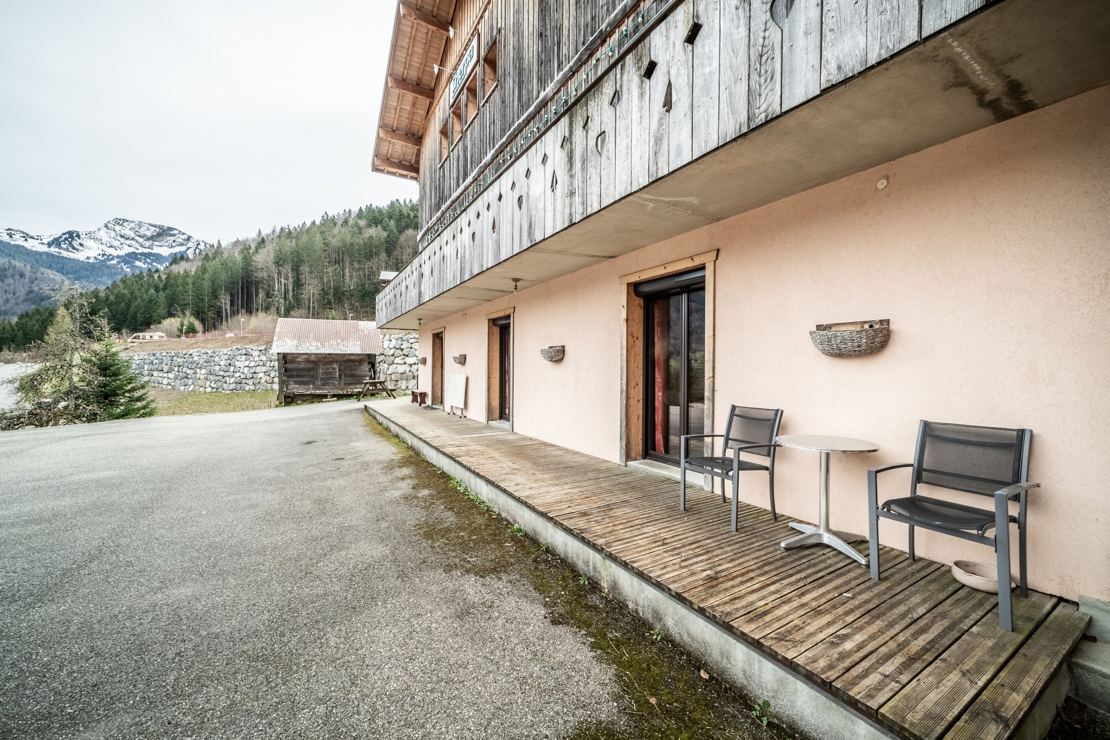 Un bâtiment doté d’une terrasse en bois, de sièges extérieurs et offrant une vue sur la montagne.
