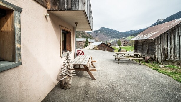 Un bâtiment rustique avec une façade en bois, un chemin de gravier et une table de pique-nique.