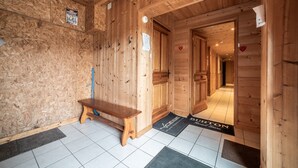 Un intérieur en bois avec un banc, une porte ornée d’un motif en forme de cœur et une enseigne portant l’inscription « BURTON ».