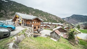 Un chalet de montagne avec des cabanes en bois, un télésiège et un parking.
