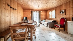 Un intérieur en bois comprenant une table à manger, des chaises, un canapé et un fauteuil rouge.