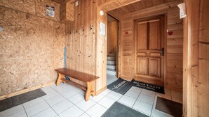 A wooden interior with a bench, a door, and a staircase.