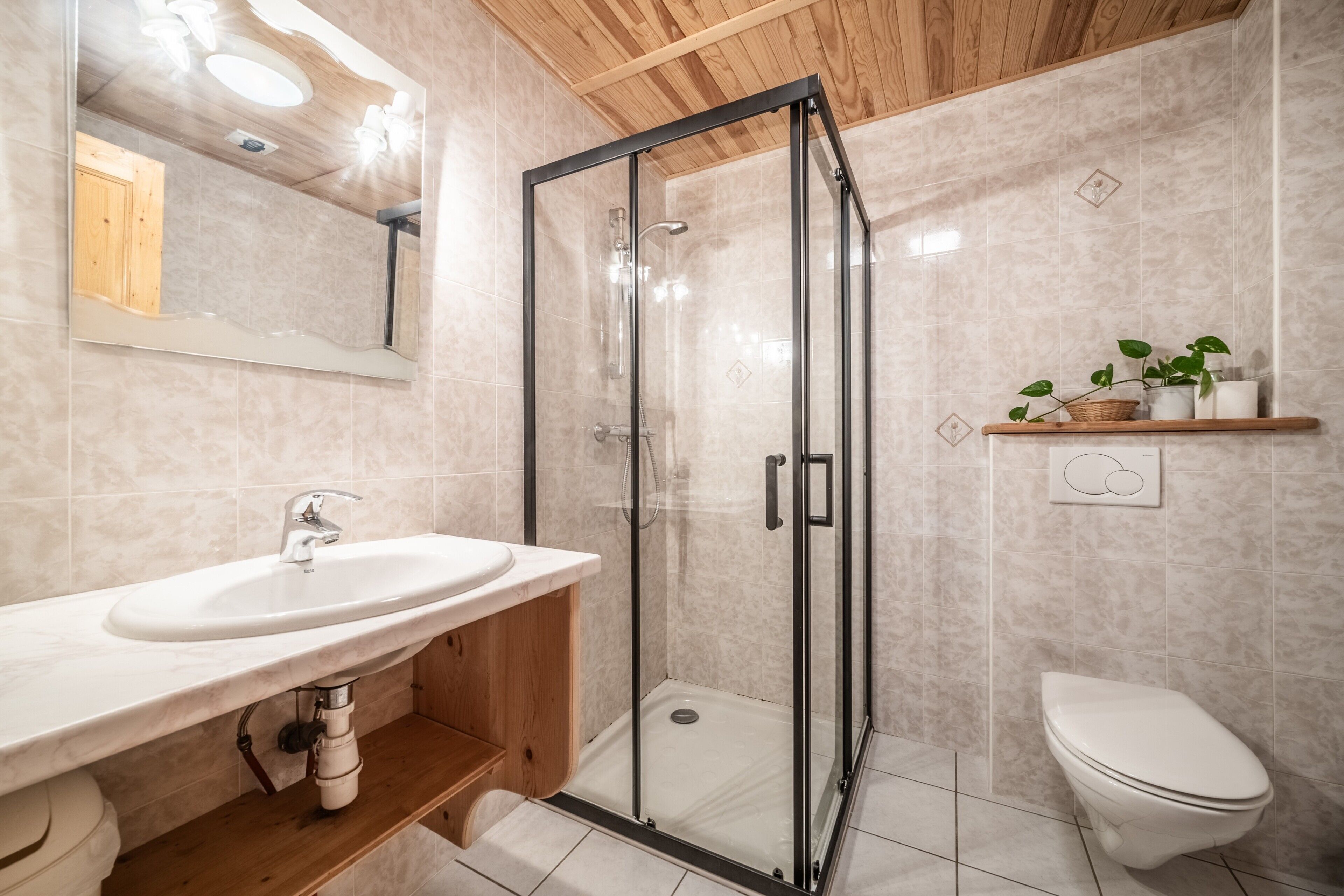 A bathroom with a glass shower enclosure, a sink, and a toilet.