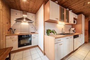 Eine moderne Küche mit Holzausstattung, einer Edelstahl-Dunstabzugshaube und einer eingebauten Mikrowelle.