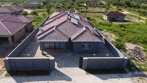 A residential building with a tiled roof, a gated entrance, and a paved driveway. - Grey Mansion BnB  (Masvingo)