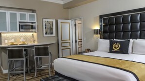 A hotel room with a bed, a desk with two chairs, a microwave, and a minibar.
