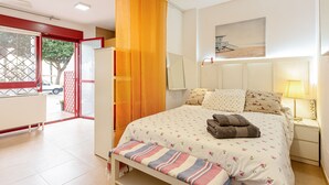 Un dormitorio con cama, mesita de noche, lámpara y vistas al exterior.