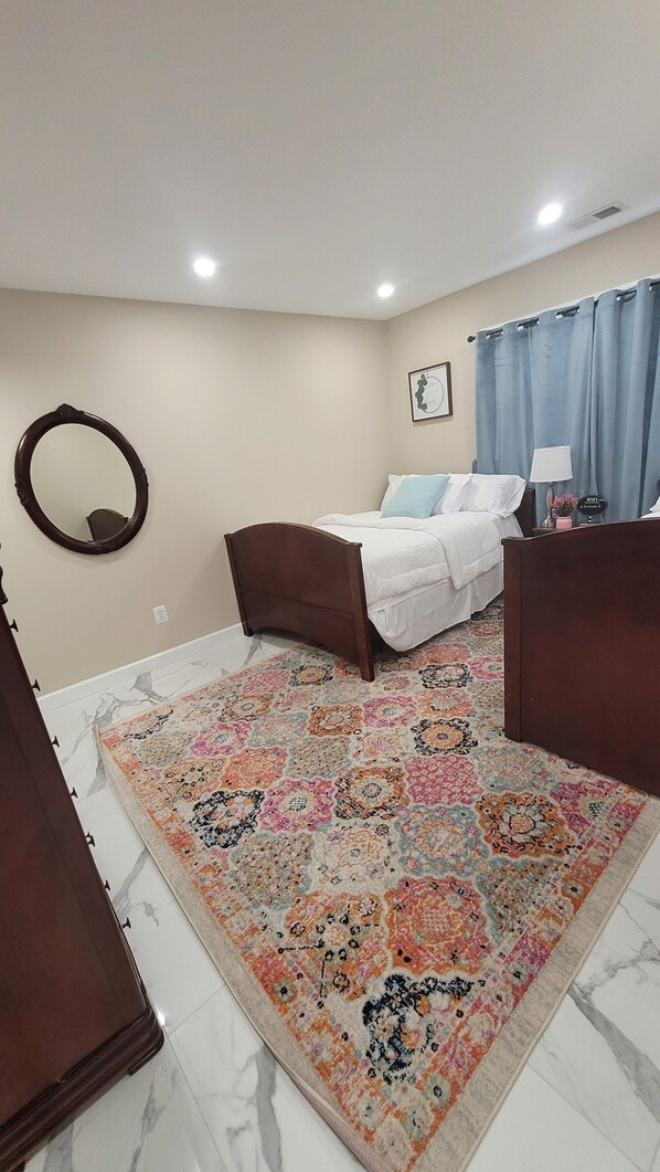 A bedroom with a bed, a large mirror, a patterned rug, and a ceiling light. - Luxury Suburban Hideaway
Come see why this is better than a hotel stay. (Clark)