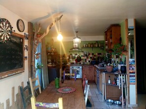 A kitchen with a wooden table, a chandelier, and a chalkboard with writing.