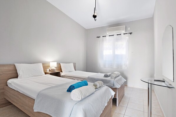 A modern hotel room with two beds, a bedside table with a lamp, a glass table, and a large mirror. - Villa Jimmy's Katomeri 2 with Sea View, Wi-Fi and Air Conditioning (?eganisi)