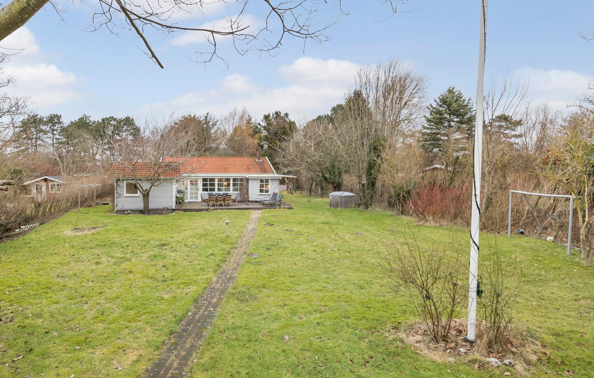 A house with a paved path leading to a patio area with outdoor furniture.