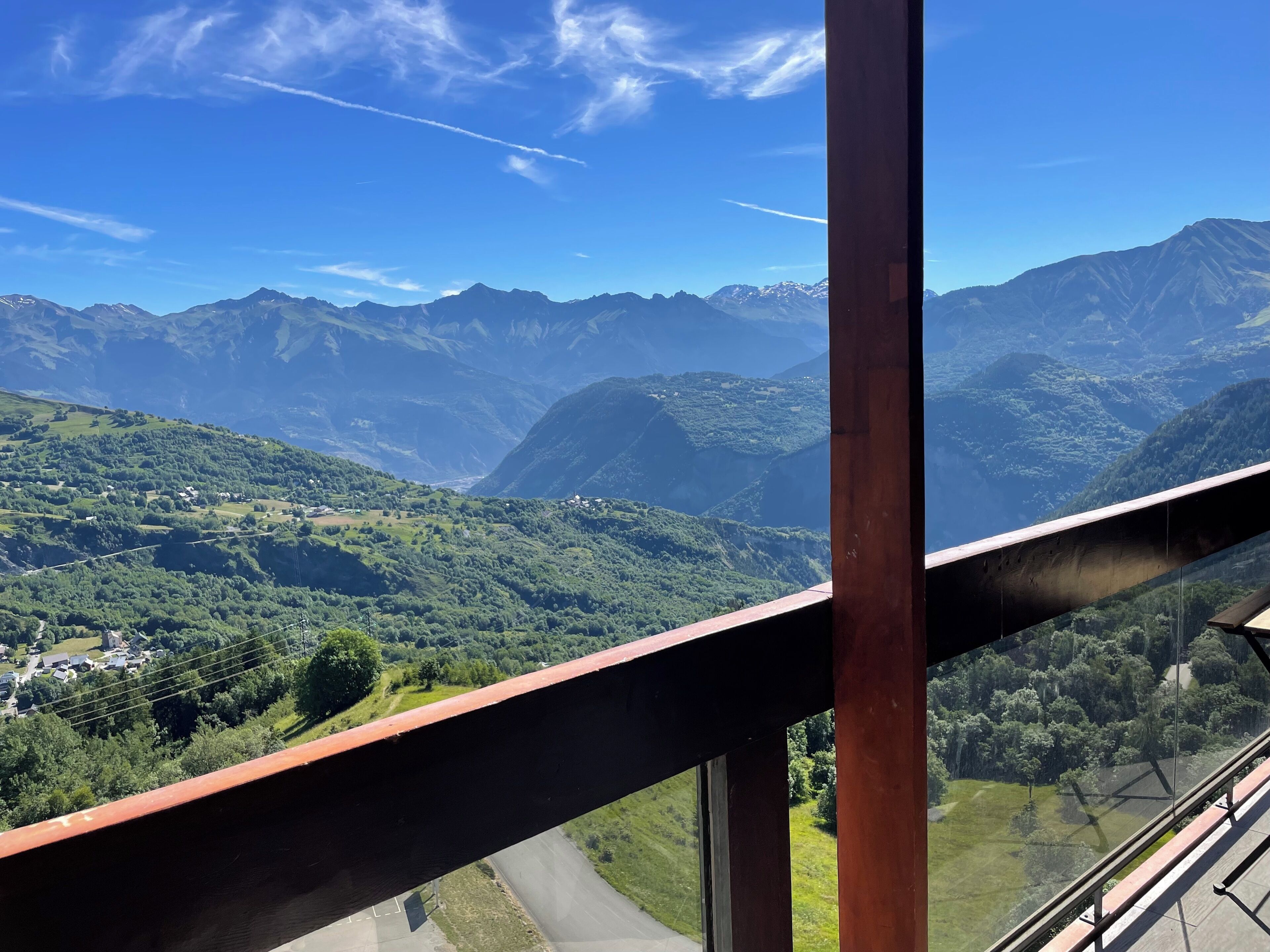 Paisaje montañoso con cielo despejado, caminos visibles y edificios en el valle.