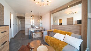 Una sala moderna con sofá, mesa de centro y comedor, con una cocina al fondo.