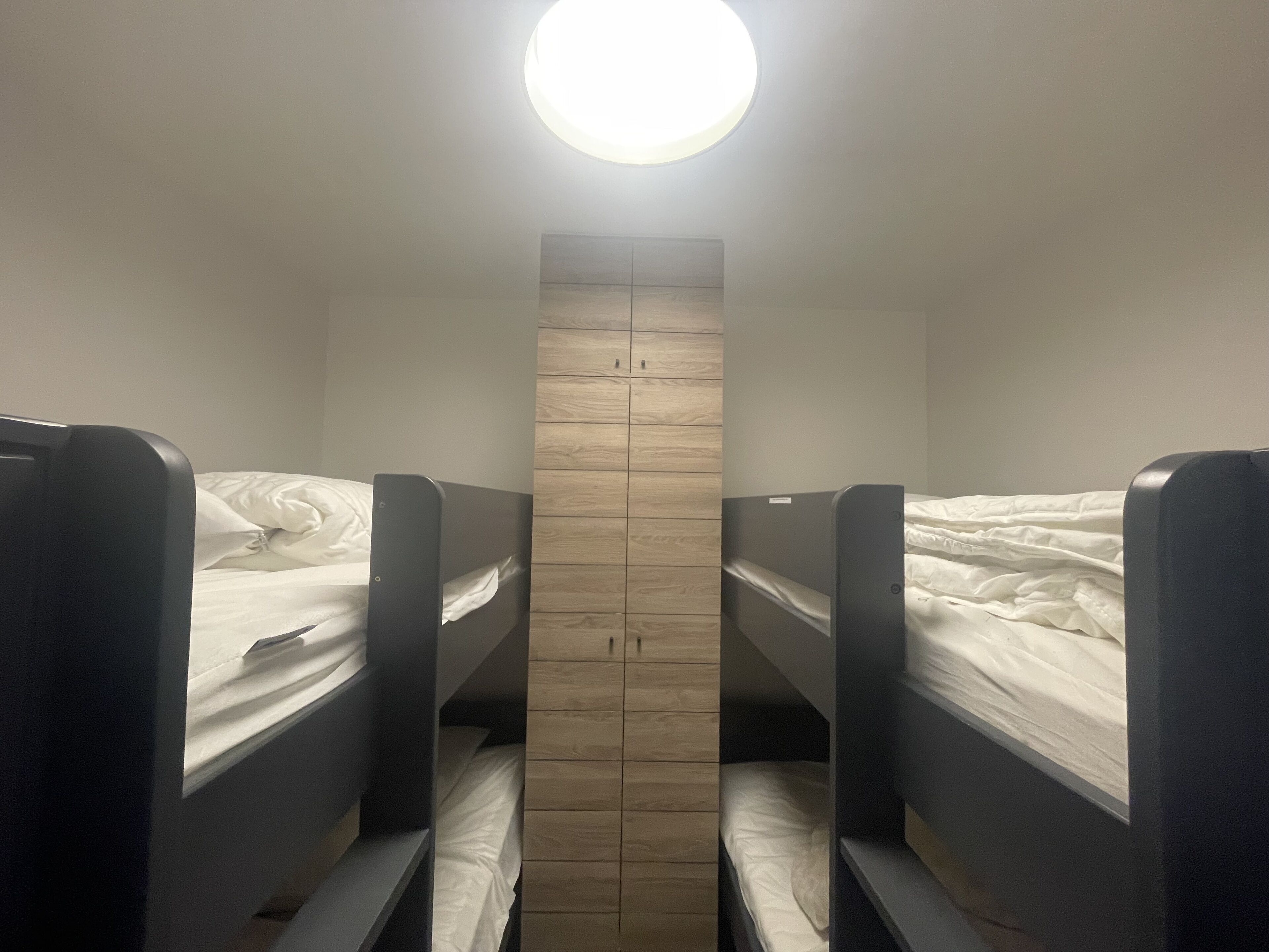 A bunk room with two beds and a wooden wardrobe.